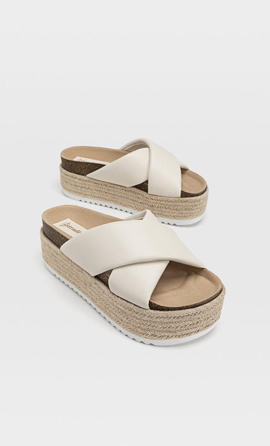 Con plataforma de yute y tiras cruzadas en material acolchado de color crudo, esta sandalia tiene un precio de 29,99 euros.