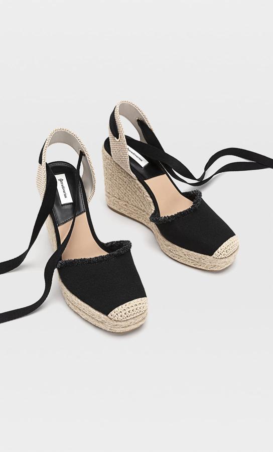 Estas cuñas de yute y tejido en color negro tienen una altura de 11 centímetros y cierre mediante tiras atadas al tobillo. Tienen un precio de 29,99 euros.