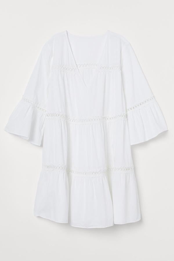 Este vestido playero corto en algodón vaporoso de color blanco con vuelo cuenta con un pronunciado escote y mangas con bordado calado. Es de H&M y tiene un precio de 29,99 euros.