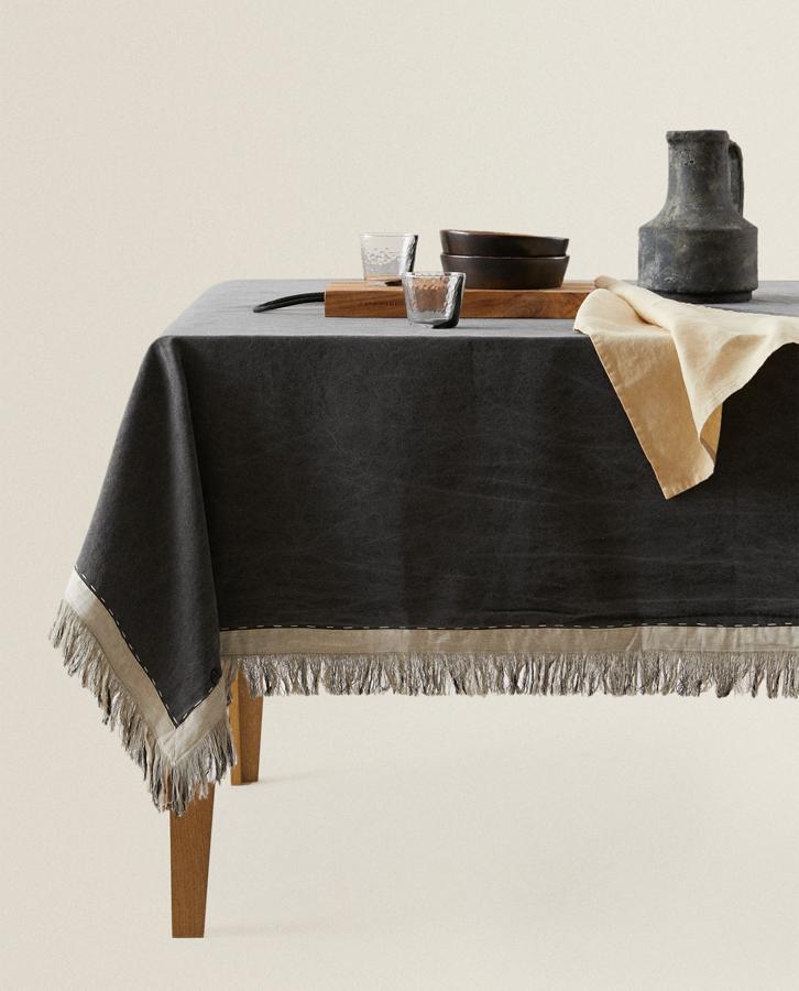 En color negro con efecto lavado, este mantel de algodón con detalle de flecos en color beige tiene unas medidas de 170x250 centímetros y un precio de 59,99 euros.