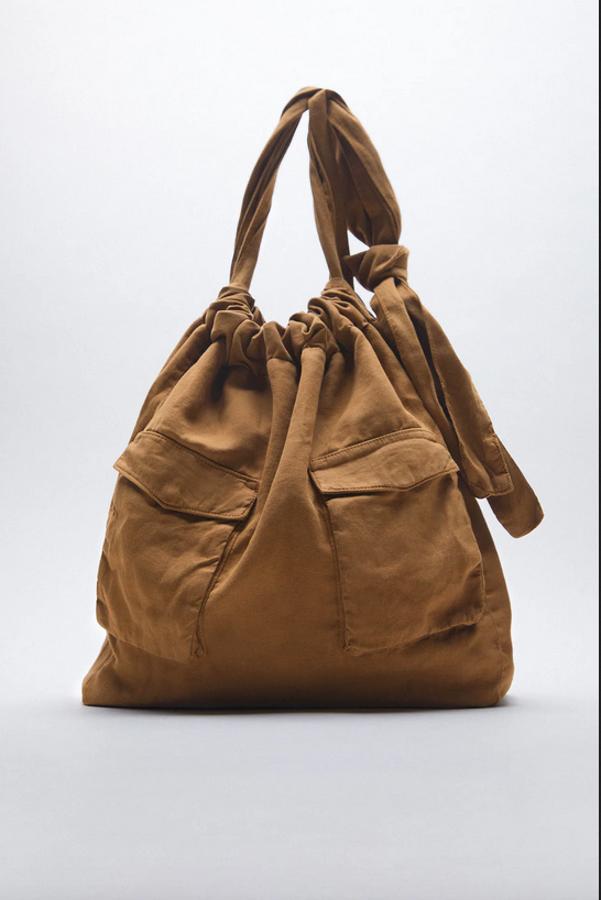 Perfecto para tus looks casual, este bolso shopper en color marrón con dos bolsillos frontales de plastrón con solapa es de Zara y viene con asas de hombro con detalle de nudo y cierre mediante fruncido. Cuesta 29,95 euros.