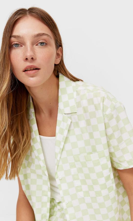 Estampado de cuadros en verde y blanco (también disponible en rosa) para esta camisa corta de cierre frontal de botones, bolsillo de plastrón en la pechera y mangas cortas. Por 15,99 euros podemos encontrarla en las tallas S, M y L.
