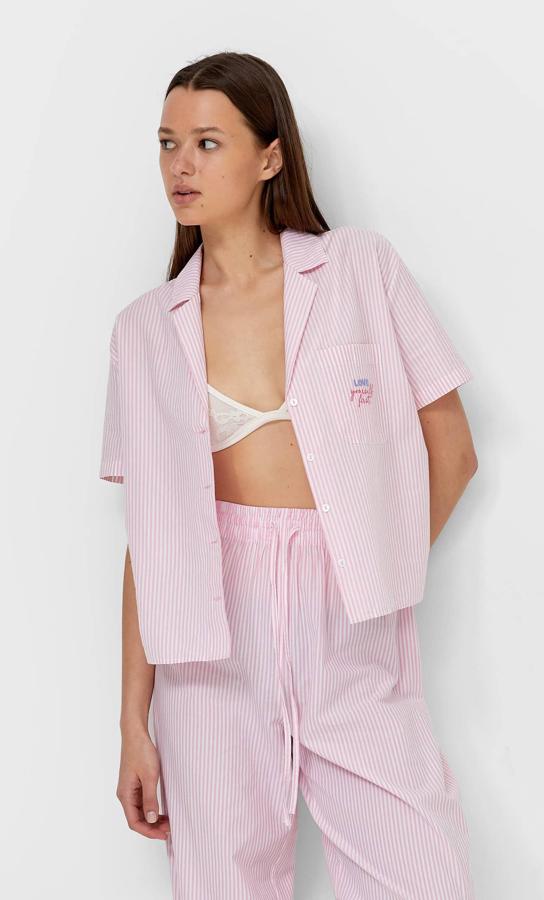 De manga corta, cierre de botones frontal, cuello de solapa y bolsillo de plastrón en la pechera, esta camisa corta de popelín con rayas rosas y blancas también está disponible en azul, tiene un precio de 15,99 euros y podemos encontrarla en las tallas S, M y L.