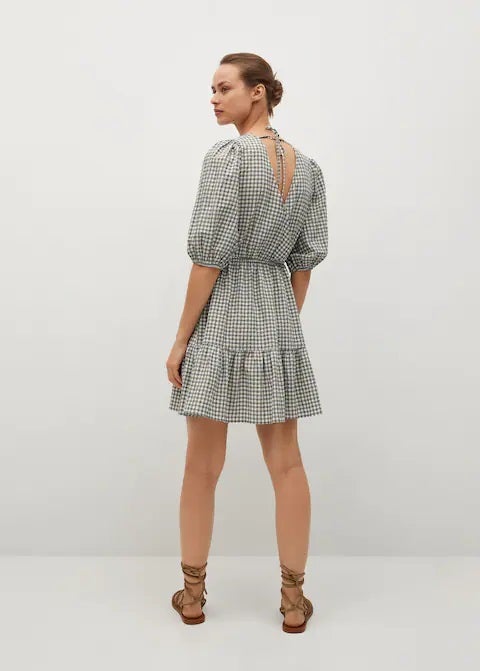 Vestido mini de Mango con estampado de cuadros vichy, escote cruzado a pico, mangas abullonadas y volantes en el bajo. Ideal para la llegada del buen tiempo. (29,99 euros).