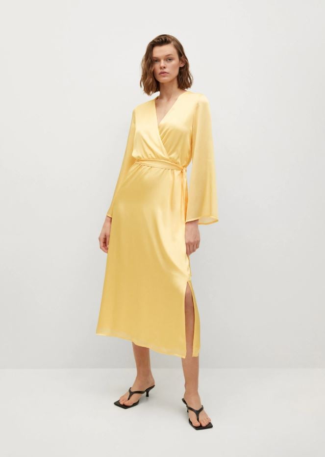 Perfecto para un look de invitada de día, este vestido midi de silueta 'wrap' en satén amarillo vainilla cuesta 59.99 euros en Mango.