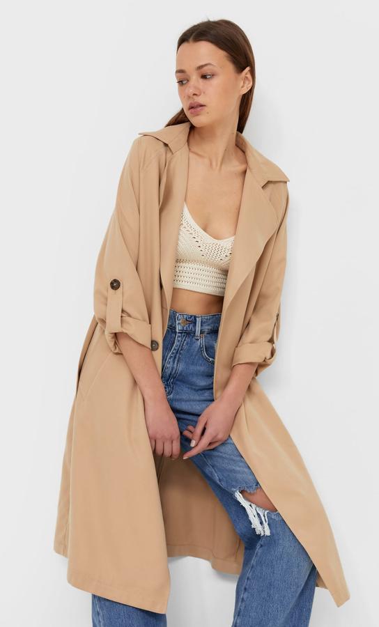 Disponible en dos tonalidades, este trench fluido con cuello solapa y detalle de cinturón del mismo tejido es de Stradivarius y tiene un precio de 39,99 euros.
