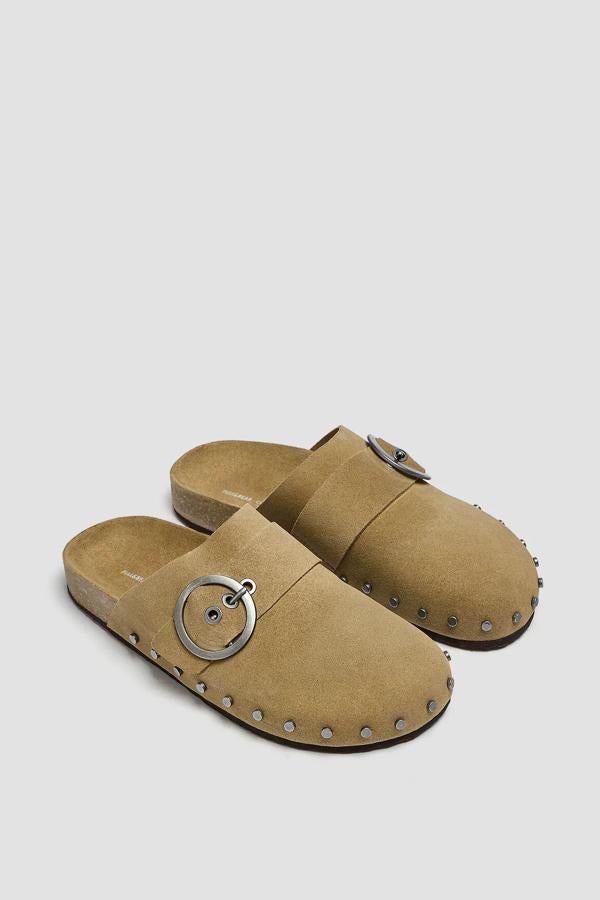 Este zapato tipo zueco de serraje de color arena cuenta con detalle de hebilla en la parte delantera y de tachas en la suela. Es de Pull & Bear y tiene un precio de 25,99 euros.
