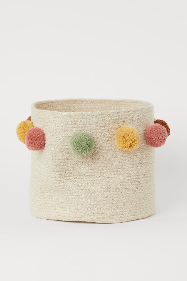 Este cesto de algodón trenzado con pompones de H&M Home (17,99 euros) es perfecto para enseñar a los peques de la casa a organizar su propio armario.