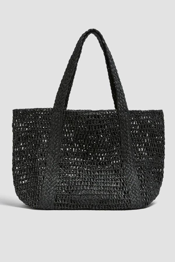 Confeccionado en tejido papel trenzado de color negro, este bolso tipo shopper con asa de hombro y cierre de imán tiene un precio de 25,99 euros.