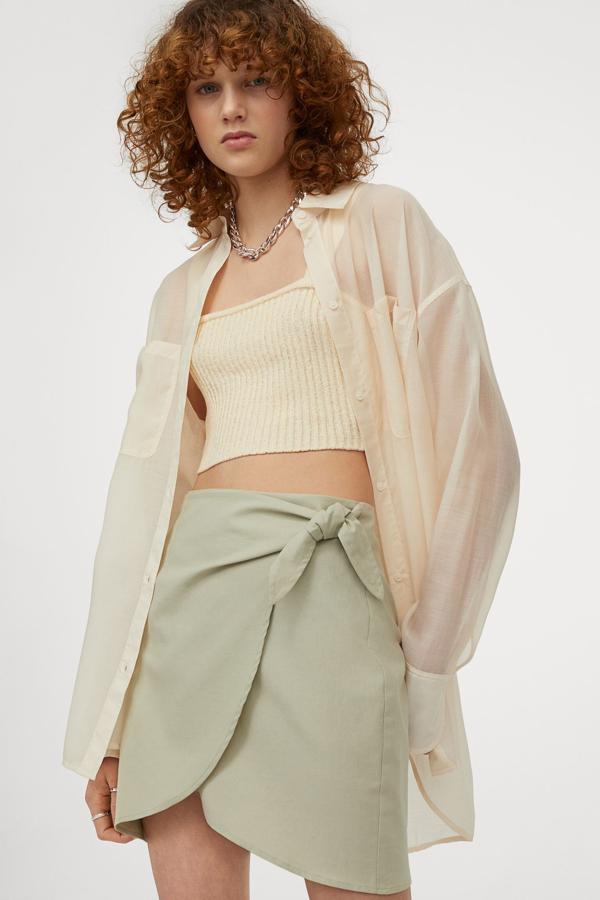 En verde claro o en negro, esta falda mini con tiras para anudar en un lateral cuenta con bajo asimétrico y diseño cruzado. Tiene un precio de 19,99 euros.