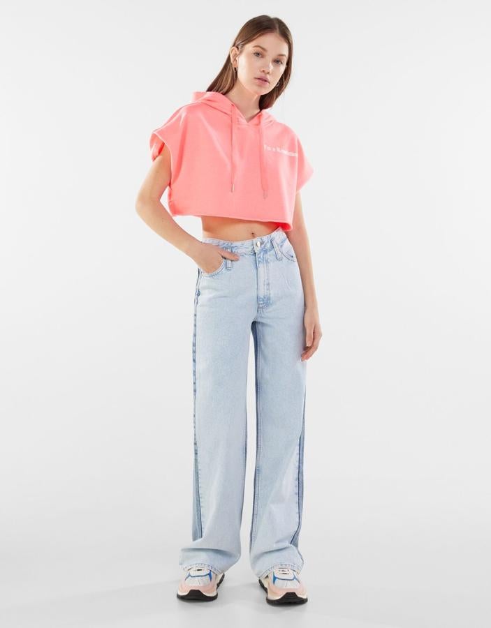 Con manga corta y capucha con cierre de cordones a tono, esta sudadera cropped de Bershka disponible en rosa y azul turquesa cuesta 15,99 euros y está disponible entre las tallas XS y L.