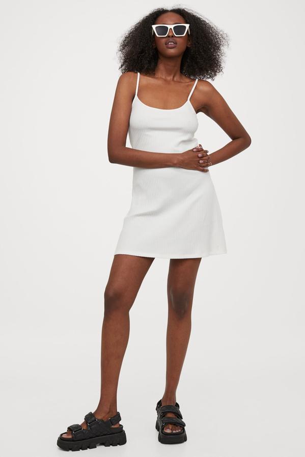De venta exclusiva en la web de H&M, este vestido blanco corto confeccionado en punto suave viene con tirantes finos, escote redondo y diseño de cintura entallada. Con falda con vuelo, podemos encontrarlo entre las tallas XXS y XL por 9,95 euros.
