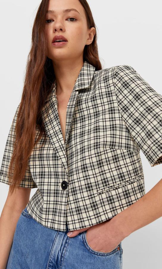 En color crudo con estampado de cuadros, esta blazer de manga corta y diseño cropped con abertura en la espalda es de Stradivarius y viene con cierre frontal de botón. Cuesta 25,99 euros y está disponible entre las tallas XS y XL.