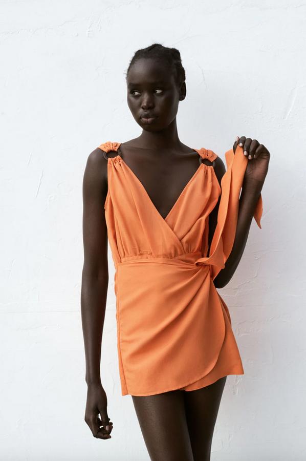 Confeccionado en mezcla de algodón y lino, este mono corto naranja de Zara con escote de pico cruzado y manga sisa con aplicación de arandela en los hombros, tiene detalle delantero tipo pareo con lazada en un lateral. Podemos encontrarlo entre las tallas XS y XL por 29,95 euros.