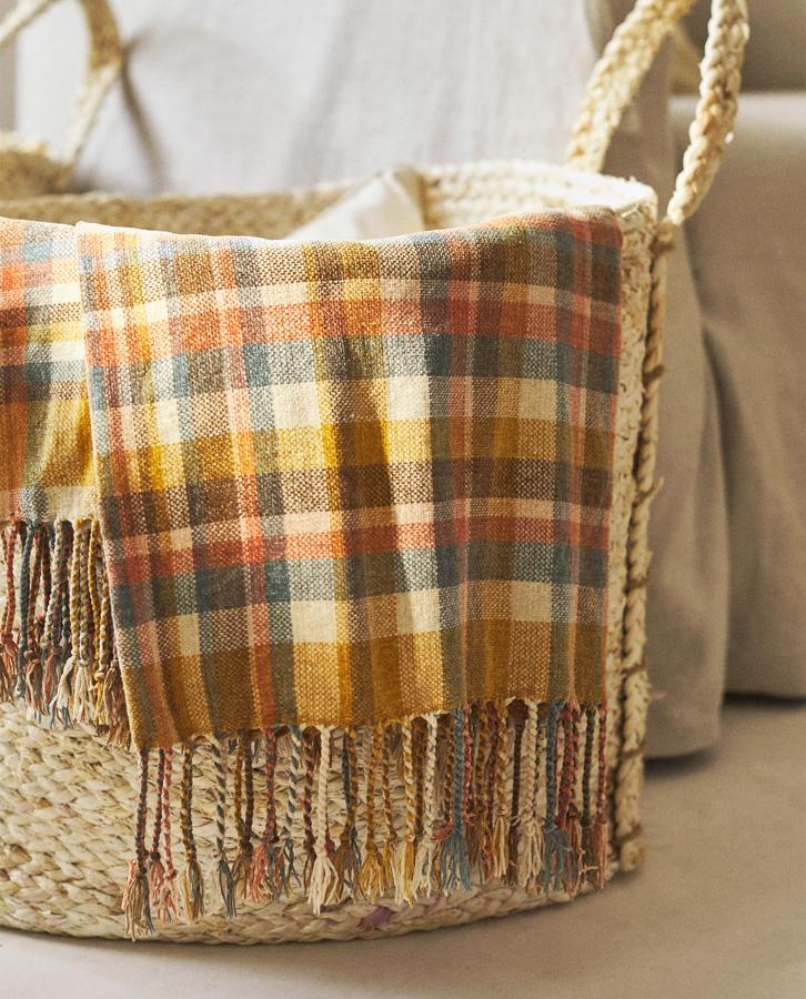 Con estampado de cuadros multicolor, esta manta de chenilla de 140x190 centímetros cuenta con acabado de flecos y un precio de 23,99 euros.