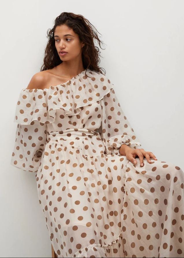 Si solo pudiéramos comprarnos un vestido esta temporada, probablemente sería este de gasa con estampado de lunares y escote asimétrico rematado con volantes que hemos encontrado en Mango (59.99 euros)