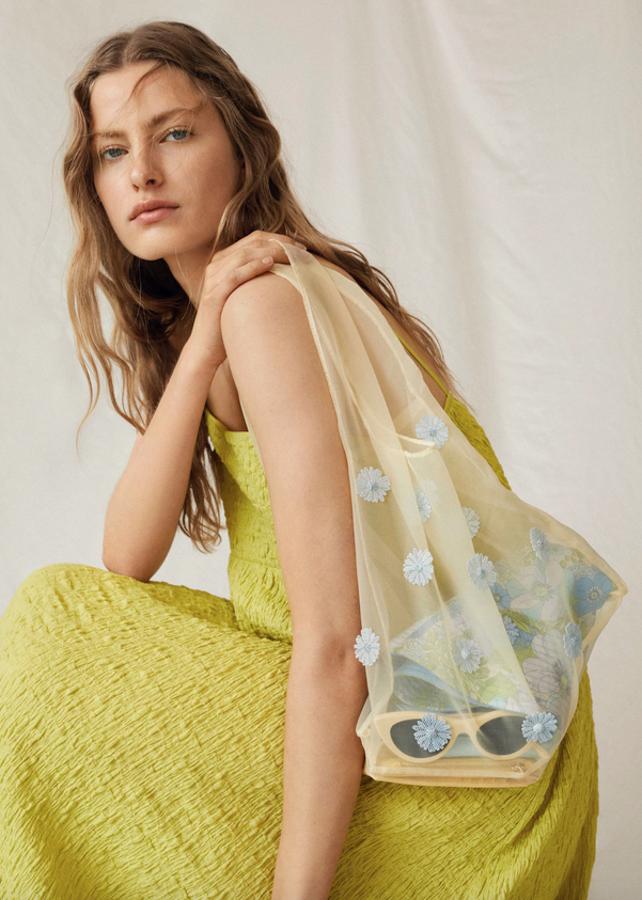 En amarillo pastel y tejido semitransparente cuadrado, este bolso de hombro teñido a mano con índigo y detalle de flores azules impresas en 3-D viene con dos asas largas anchas. Cuesta 69,99 euros.
