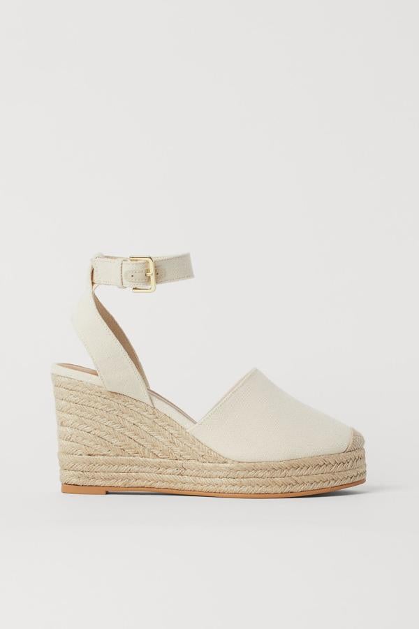 En color blanco y con una altura del tacón de nueve centímetros, estas alpargatas de lona con cuña y pulsera ajustable con hebilla de metal tienen un precio de 29,99 euros.