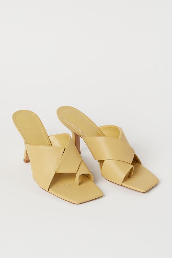 En amarillo o en blanco, estos mules en piel sintética con tiras anchas cruzadas en el empeine y tira para el dedo tienen un precio de 29,99 euros.