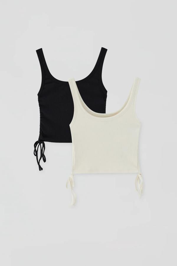 Confeccionados en algodón orgánico, estos tops cropped de tirantes y escote redondo cuentan con frunces laterales y tienen un precio de 15,99 euros.