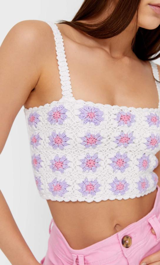 De escote recto, tirantes y detalle en la espalda en nido de abeja, este top blanco con diseño de flores lilas y rosas es de Stradivarius, cuesta 17,99 euros y está disponible entre las tallas XS y L y en color blanco y negro.