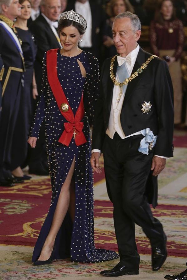 En 2018, la Reina llamó la atención con un vestido azul marino bordado con perlas que simulaban lunares, de Ana Locking, y con abertura lateral. Lo estrenó para lacena de gala celebrada en el Palacio Real de Madrid en honor del presidente de Portugal, Marcelo Rebelo de Sousa. En esa ocasión lució la tiara Cartier.