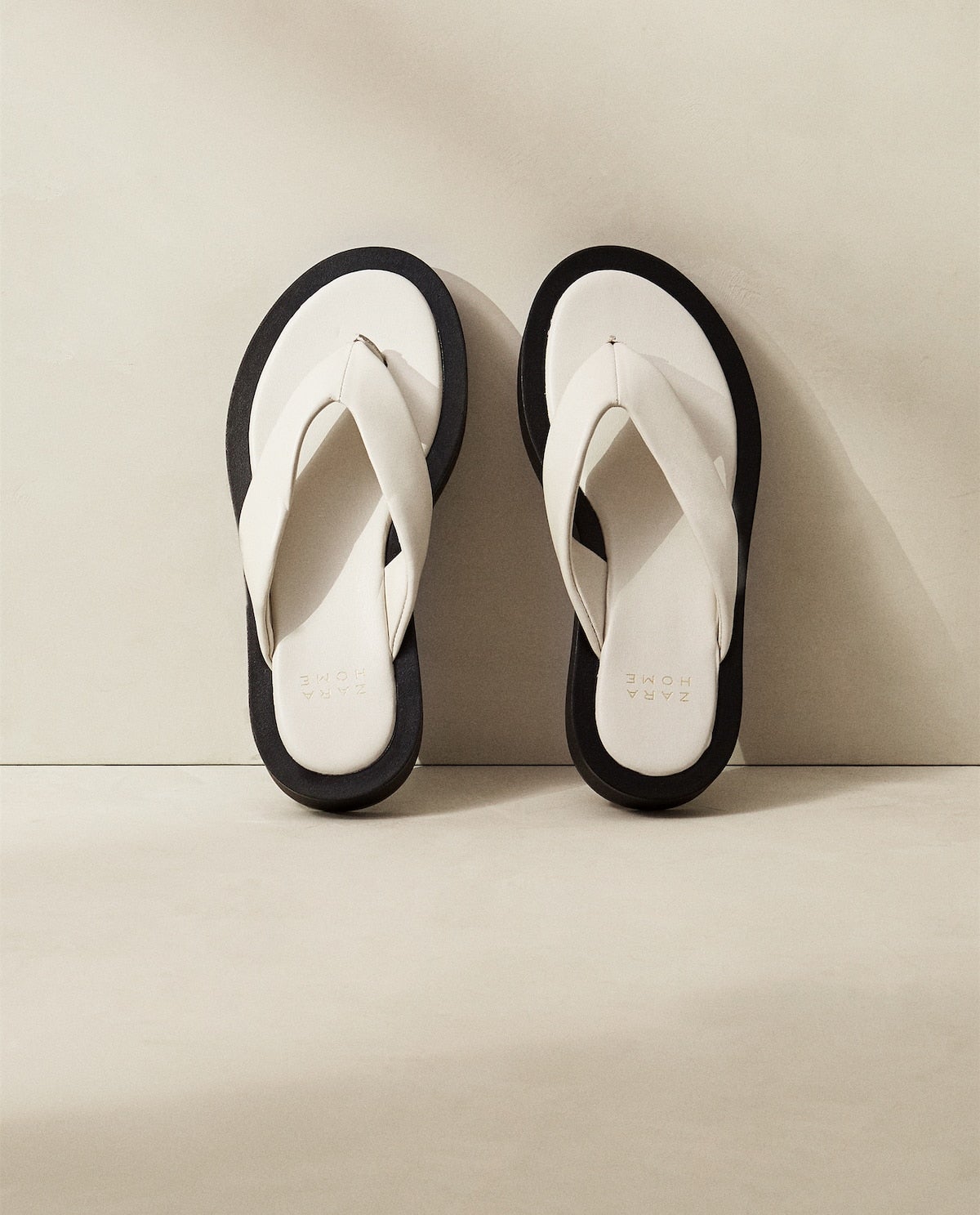 Sandalias de dedo en blanco y negro a contraste con tejido de piel y con una plataforma de 2,5 centímetros. Un básico muy funcional que arrasa entre las influencers porque imitan a unas de lujo por muy poco. Encuéntralas en Zara Home por 29,99 euros.