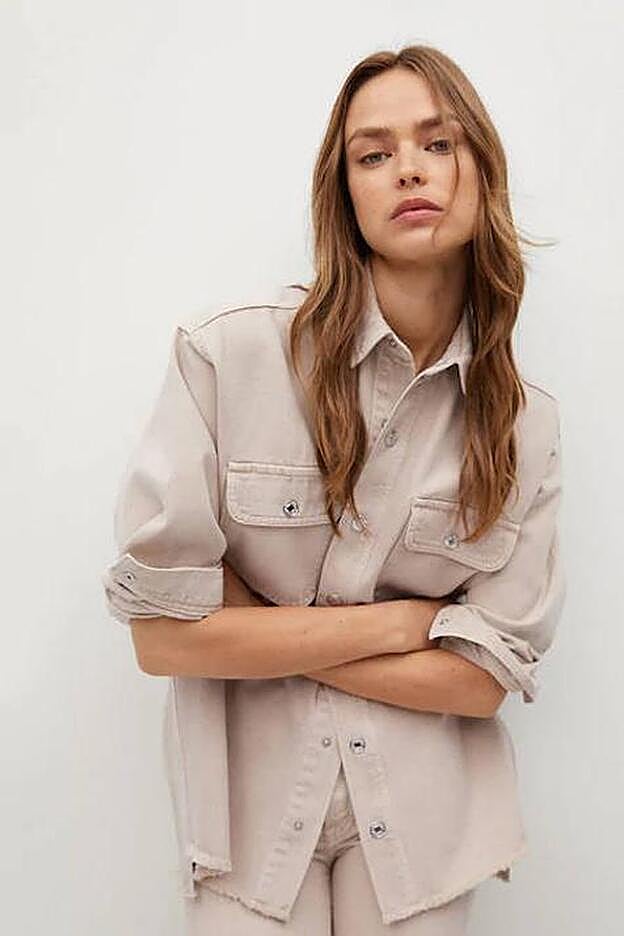 La sobrecamisa es de tejido denim y color beige