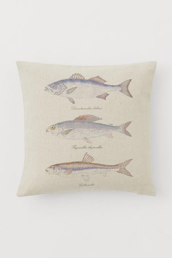 Los detalles de peces siempre quedan bien en las casas de estilo mediterráneo. Añádelo en pequeñas dosis. Una opción asequible es esta funda de cojín que cuesta 7,99 euros.
