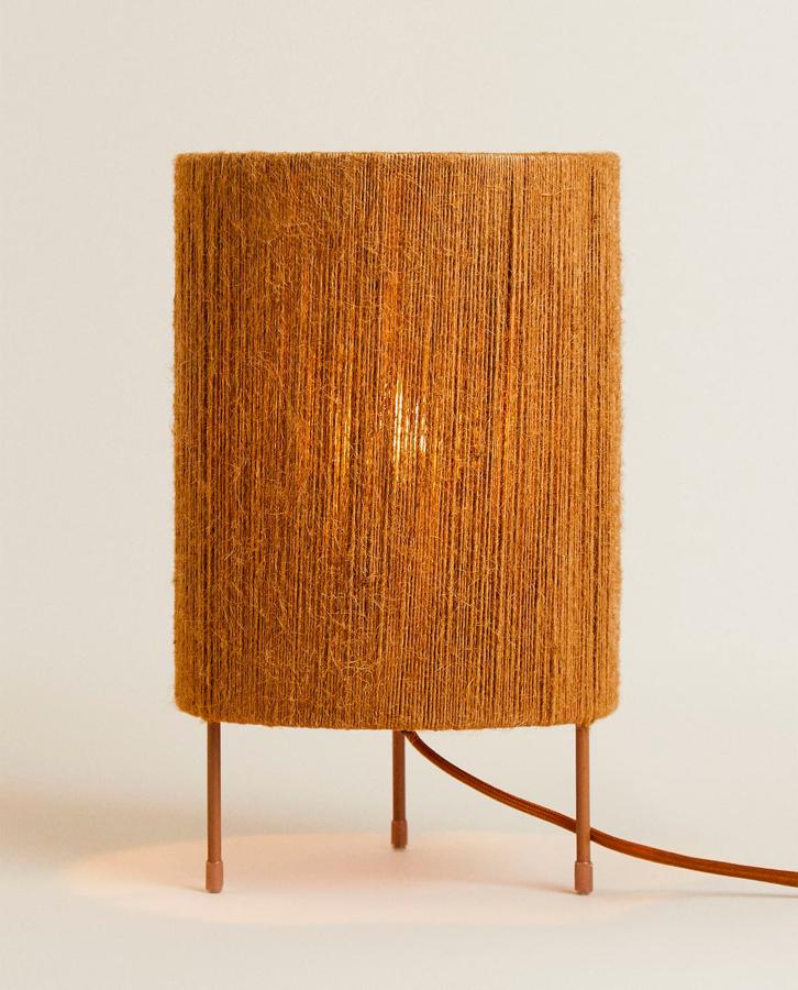 Esta lámpara de sobremesa nos ha enamorado. Es una lámpara pequeña con patas de hierro y pantalla de yute. Está disponible en Zara Home y por 39,99 euros.