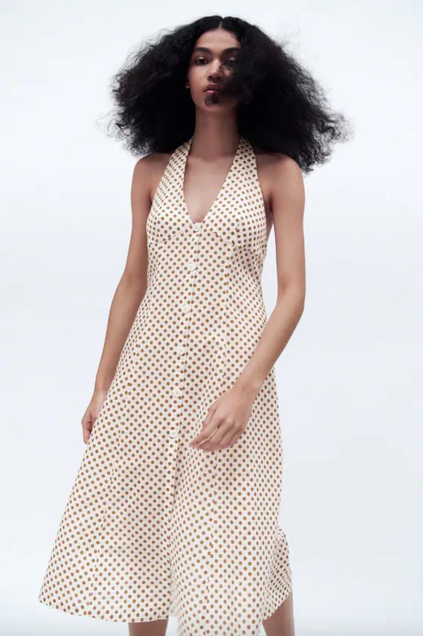 Confeccionado en tejido con mezcla de lino, este vestido blanco con lunares en mostaza tiene el escote de pico con cuello halter con lazada y cierre frontal de botones a tono. Con un precio de 29,95 euros, está disponible entre las tallas XS y XL.