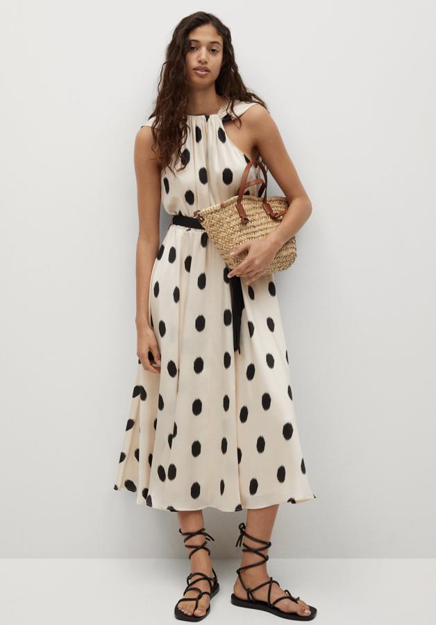 En color blanco roto y con topos de color negro, este vestido fluido con cuello halter y cinturón desmontable es de Mango y tiene un precio de 59,99 euros.