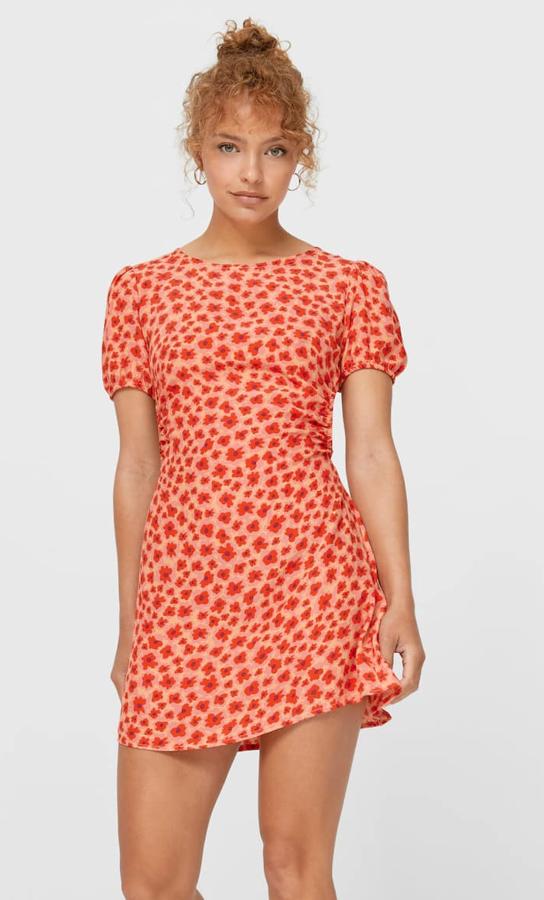 Este vestido corto con cuello redondo y manga corta abullonada cuenta con espalda abierta con lazadas y bajo acabado en volante. En color rojo con estampado floral, tiene un precio de 17,99 euros.