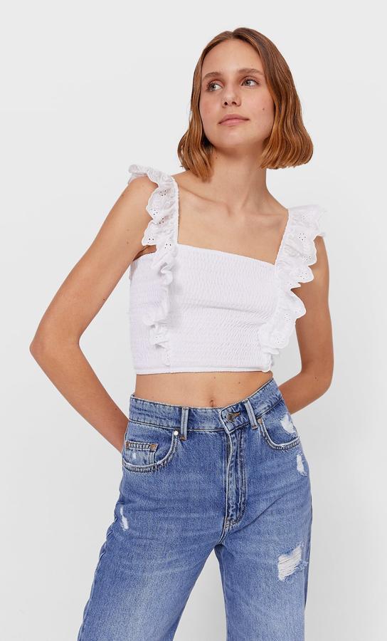 Con escote cuadrado y sin mangas, este top con bordado suizo en los volates de tirante que se extienden por el cuerpo es de Stradivarius y viene con cuerpo en nido de abeja. Con un precio de 15,99 euros, podemos encontrarlo en las tallas XS, S y M.