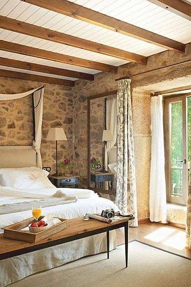 Dormitorio de estilo rústico con ropa de cama en blanco.