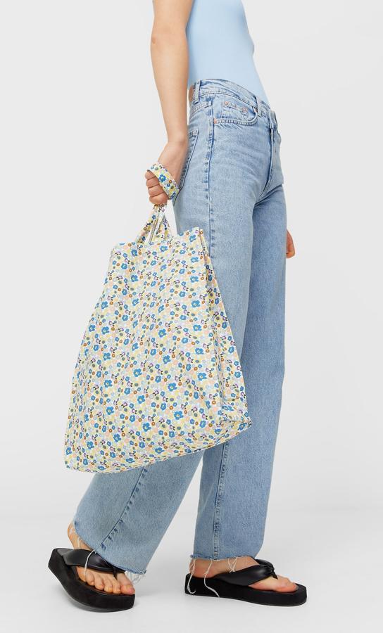 Este bolso shopper de Stradivarius de diseño vertical con estampado de flores azules y rosas viene con asas largas y cuesta 9,99 euros.
