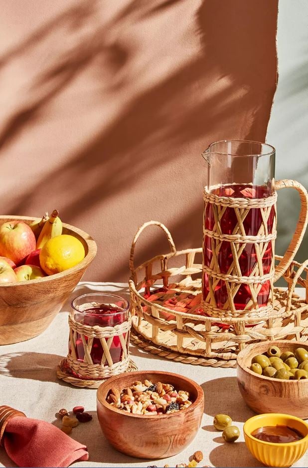 La mesa se convierte en el centro de reunión del verano, y el menaje de madera en una solución llena de estilo y, además, sostenible. La jarra de ratán cuesta 9 euros en Primark Home; el pack de 2 vasos a juegos, 6 euros y la bandeja de ratán, 10 euros.