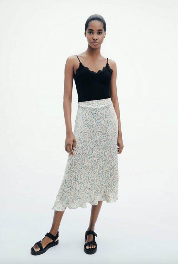 De tiro alto, con diseño midi y bajo acabado en volante, esta falda midi de Zara en color crema con estampado floral en tonos azules viene con botones laterales forrados a tono y tejido satinado. Con un precio de 29,95 euros, podemos encontrarla en las tallas XS, L y XL.