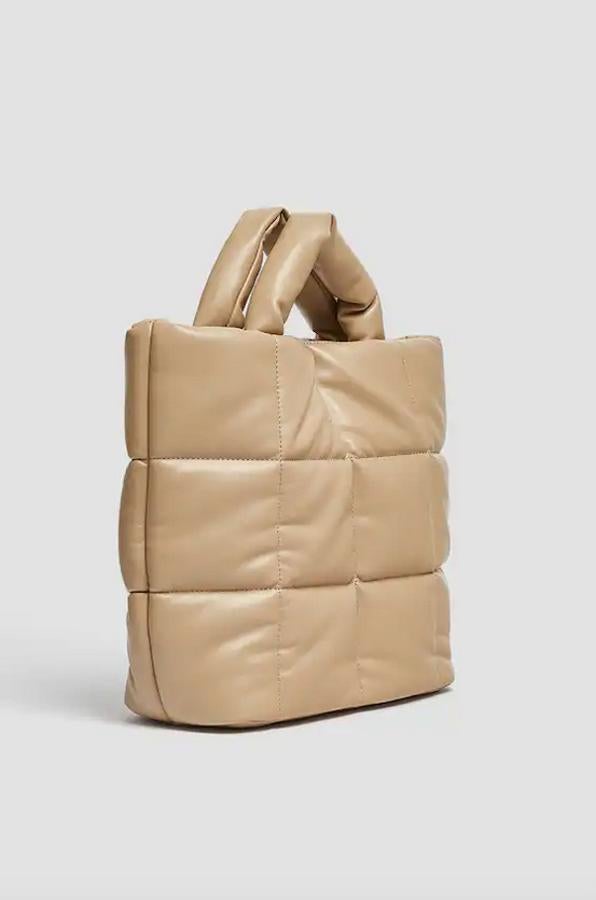 Cuerpo acolchado con detalle de pespuntes en color beige para este shopper acolchado con asa de mano y asa de hombro ajustable y extraíble que tiene el interior forrado con bolsillo y cierre superior con imán. De 25,99 euros ha pasado a costar 15,99 euros.
