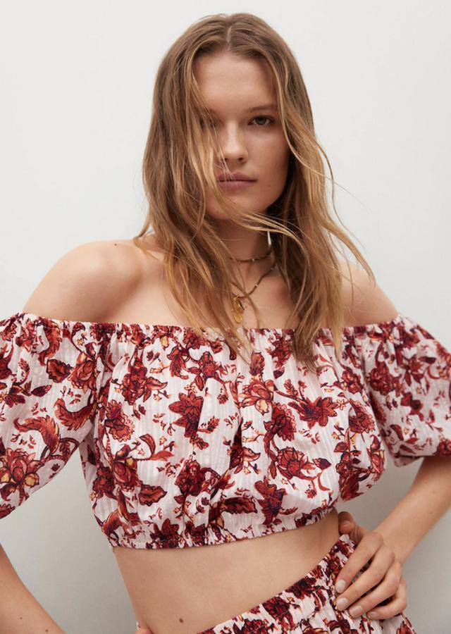Para las que buscan diseños estampados este top de algodón blanco con estampado de flores rojas y naranjas de diseño de hombros al aire cropped viene con mangas cortas abullonadas y terminaciones elásticas. Con un precio de 19,99 euros, está disponible entre las tallas XS y XL. 