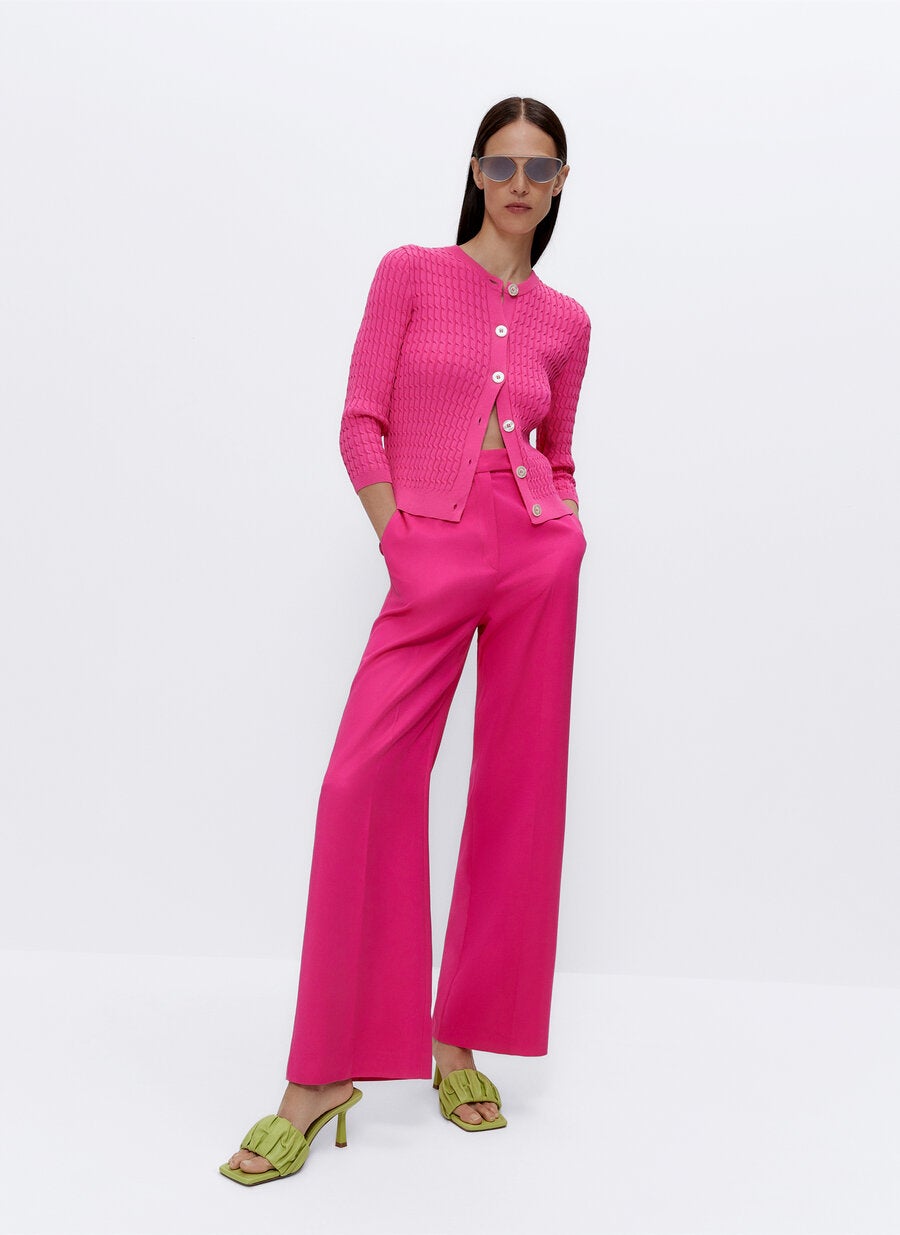 Pantalón recto de talle alto (79 €) combinado con rebeca de punto trenzado (79 €) y sandalias acolchadas (89 €), todo de Uterqüe.