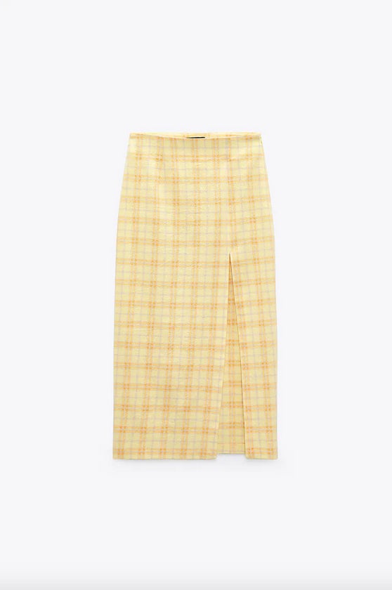 Estampado de cuadros anaranjados sobre fondo amarillo pastel para esta falda midi de tiro alto con bajo con abertura en delantero por encima de la rodilla y cierre lateral con cremallera oculta en costura. Confeccionada con al menos un 25% de algodón orgánico, está disponible entre las tallas XS y XL por 25,95 euros. 