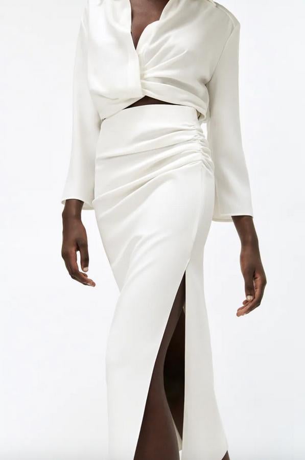 Disponible en negro o en blanco, esta falda midi de tiro alto con detalle de pliegues en un lateral, para un precioso efecto drapeado, y bajo acabado en abertura por encima de la rodilla, cuesta 29,95 euros y está disponible entre las tallas XS y XXL. 