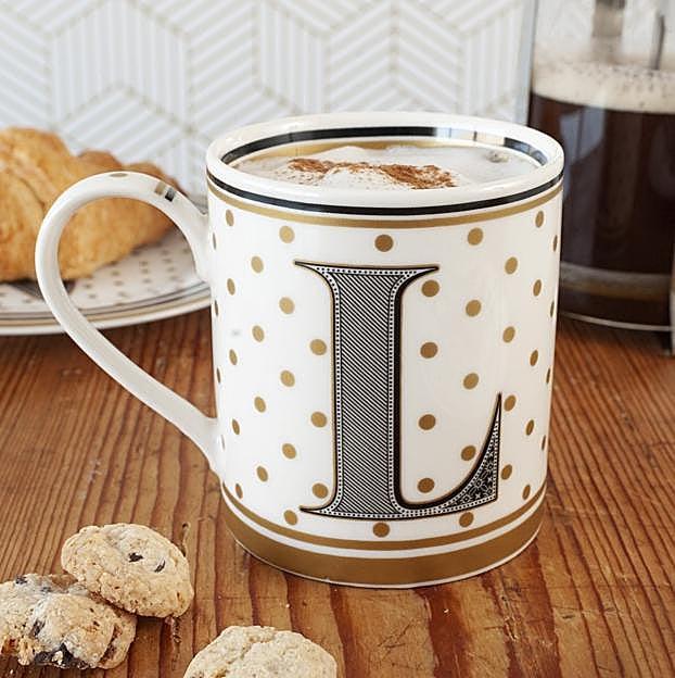 Taza con inicial 'L' en dorado, blanco y negro.