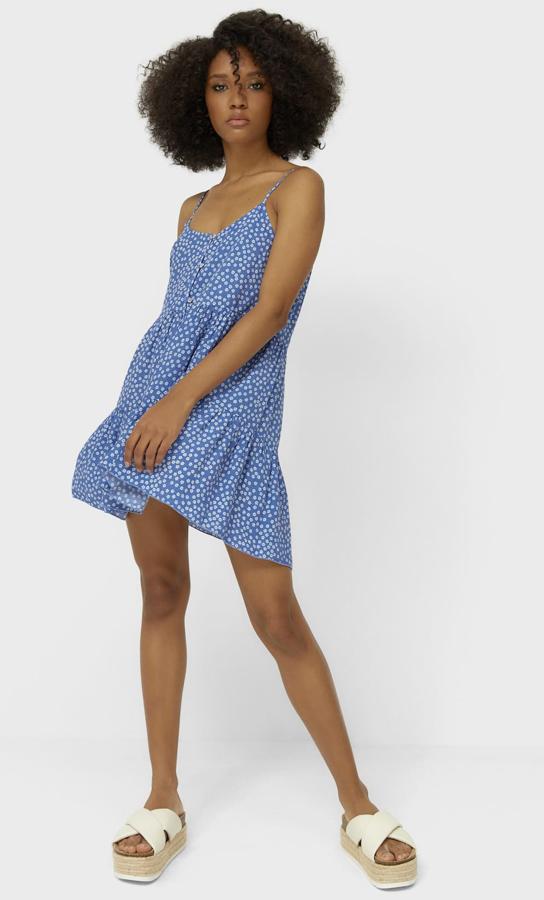 Con tirantes finos y escote recto, este vestido azul con estampado de margaritas cuenta con volante en el bajo y botones en la parte delantera. Es de Stradivarius y tiene un precio de 19,99 euros.