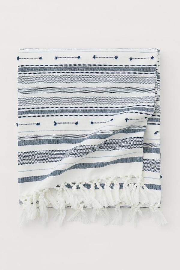 Si te gusta el estilo marinero, entonces te recomendamos apostar por esta manta (17,99 euros) de H&M Home. De rayas, en tonos azules, y perfecta para terraza con sabor mediterráneo.