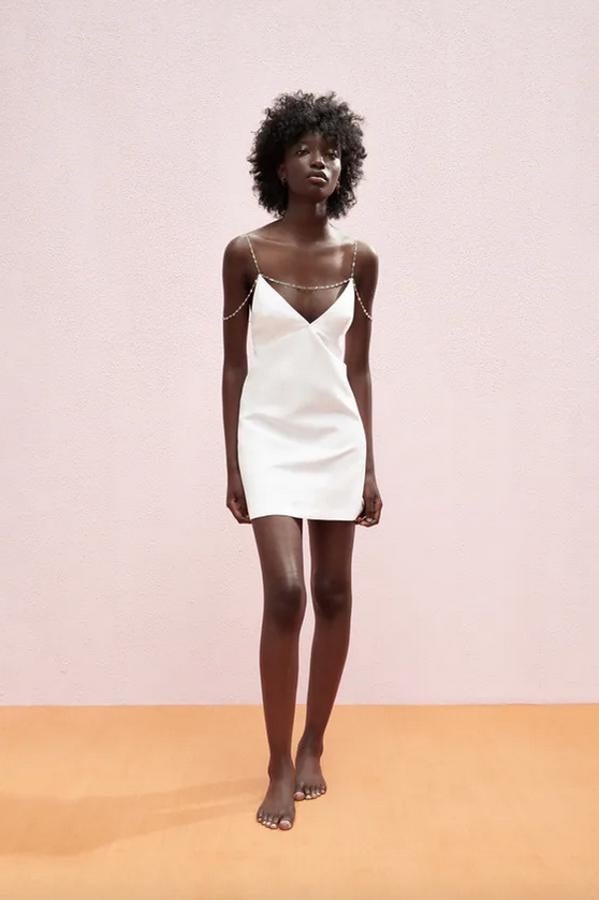 En blanco roto, de diseño corto y confeccionado con tejido en mezcla de lino, este vestido con escote de pico y tirantes metálicos con aplicación joya y bajo acabado en línea evasé ha pasado de 39,95 euros a 29,99 euros.