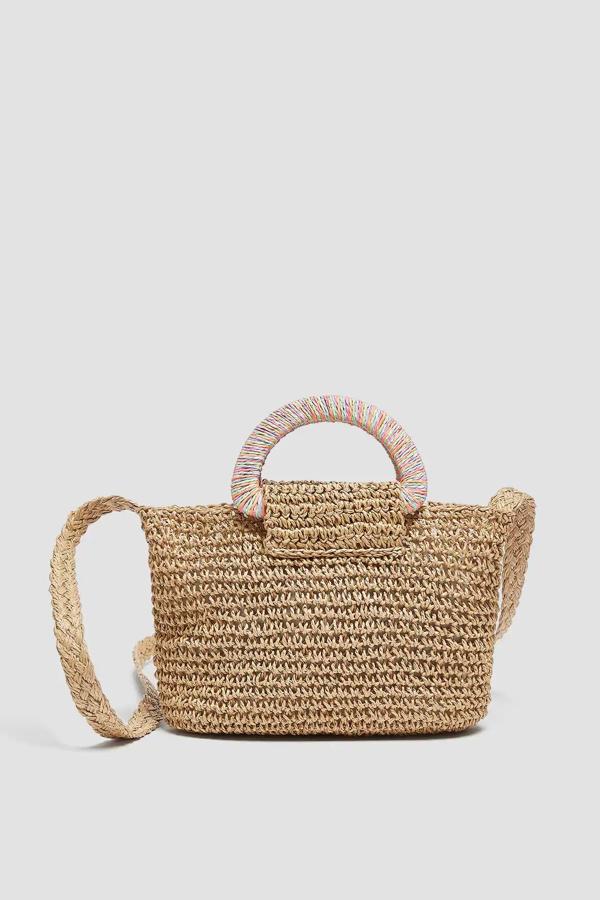 Este bolso tipo bandolera de papel trenzado en color beige cuenta con detalle de asas de mano multicolor y asa larga de hombro. Tiene un precio de 15,99 euros.