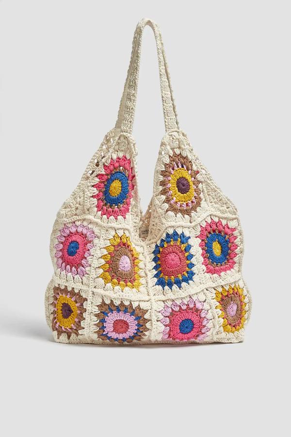 En color crudo con flores de colores, este bolso shopper en tejido crochet con asas de hombro tiene un precio de 29,99 euros.