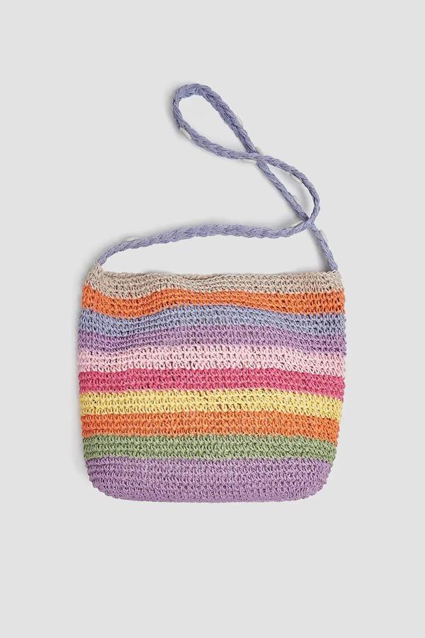 Confeccionado en papel trenzado, este bolso tipo bandolera con rayas de colores y detalle de asa de hombros con conchas tiene un precio 17,99 euros..